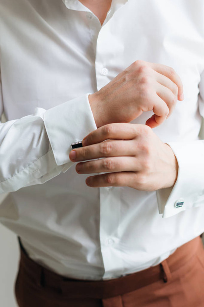 Nahaufnahme des Bräutigams, der Manschettenknöpfe im weißen Hemd trägt - Foto, Bild