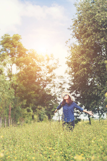 Atractiva joven mujer de pie en un campo de flores amarillas, ha
 - Foto, imagen