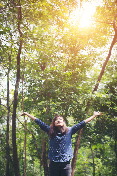 Привлекательная молодая женщина, стоящая в лесу, руки раскинуты
 - Фото, изображение