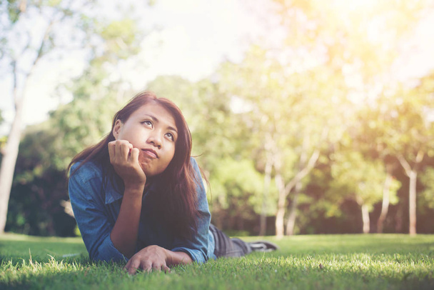 Viehättävä hymyilevä nuori hipster nainen makaa vihreällä ruoholla
. - Valokuva, kuva