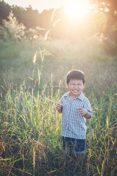 Szczęśliwy mały chłopiec azjatyckich, bawiąc się na zewnątrz. Cieszyć się życiem. Ładna Azjatka  - Zdjęcie, obraz