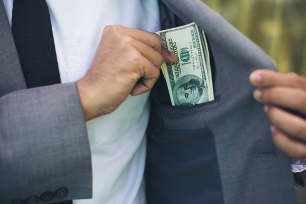 Businessman placing money into his pocket. - Фото, зображення