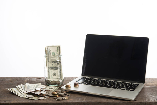 φορητό υπολογιστή με κέρματα και Δολάριο Τράπεζα που απομονώνονται σε λευκό φόντο. - Φωτογραφία, εικόνα