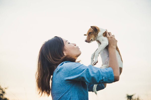 Happy hipster woman smiles and holds a small dog. Little puppy w - Photo, Image