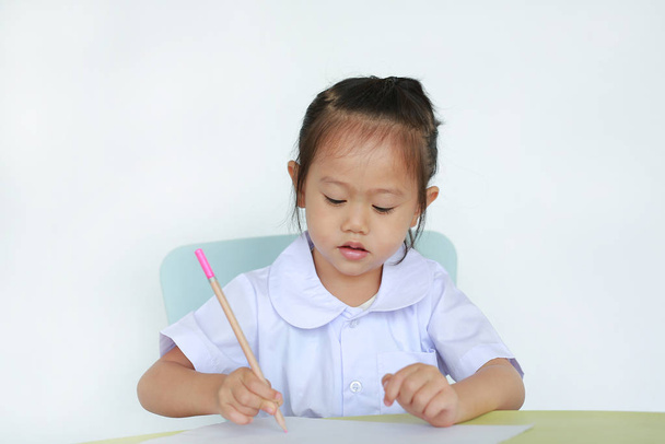 Asian child in school uniform with pencil writing on table isolated on white background. - Fotografie, Obrázek