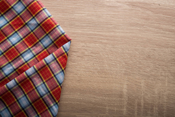 Checkered red and white napkin on wooden background. - Photo, Image