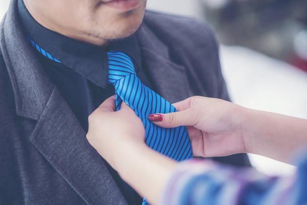 бизнесмен готовится отправиться на презентацию проекта и ассистент поможет настроить галстук
 - Фото, изображение