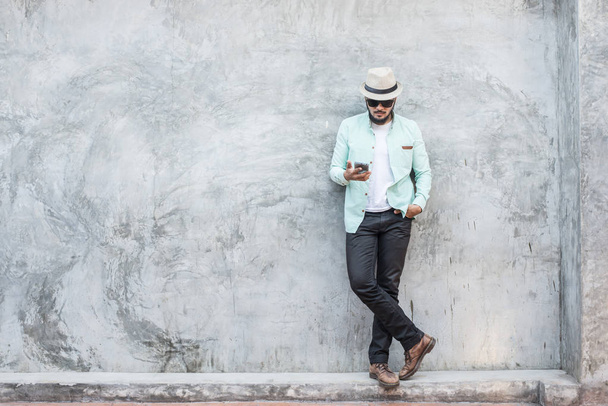 Retrato de joven hipster guapo usando un teléfono inteligente contra
  - Foto, imagen