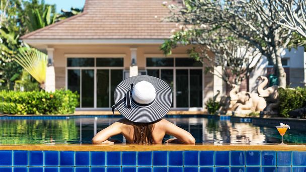 夏の休暇の概念、水着の女性は、ビキニとカクテルのプールの近くで帽子の若いセクシーな女性プールでカクテルでリラックスできます。夏の休日、旅行、人と休暇の概念 - 写真・画像