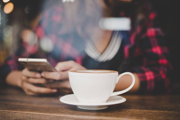 Bokovky ženská ruka v kavárně s pomocí mobilních telefonů a SMS - Fotografie, Obrázek