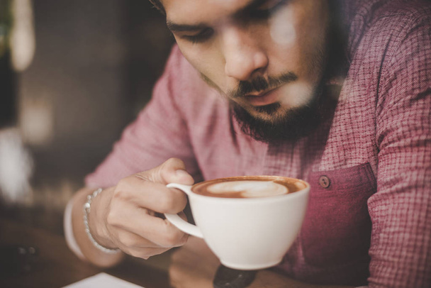 Молодой человек смотрит в сторону, сидя в баре в кафе и дрин
 - Фото, изображение