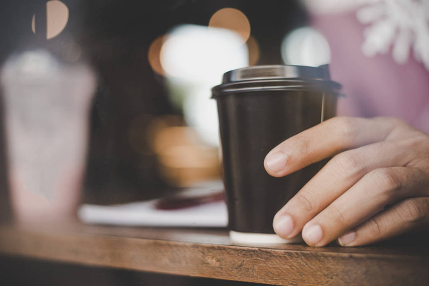 Zbliżenie: młody człowiek trzyma kawy na wynos w wcześnie rano - Zdjęcie, obraz