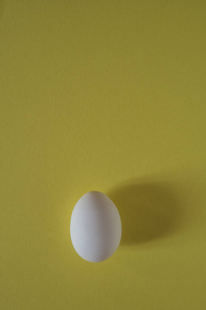 White egg on a yellow background top view - Foto, Imagem