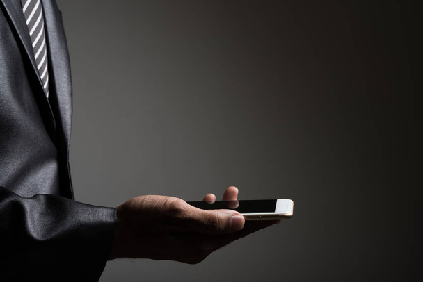 Businessman with his smartphone isolated on black. - Foto, immagini