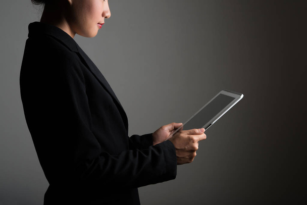 Mujer sosteniendo en la tableta digital y mirando en una pantalla en blanco
. - Foto, Imagen