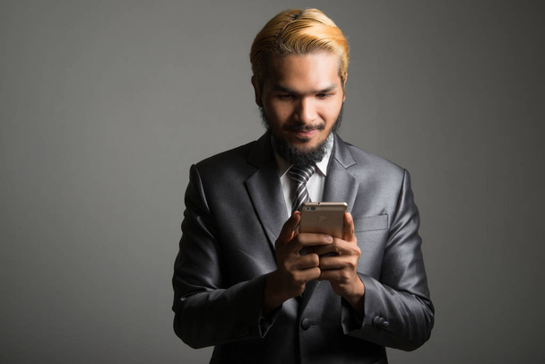 Young businessman using mobile phone isolated on black. - Photo, Image