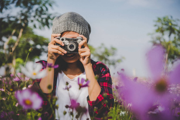 Hipster menina com foco câmera vintage atirando flores em garde
 - Foto, Imagem
