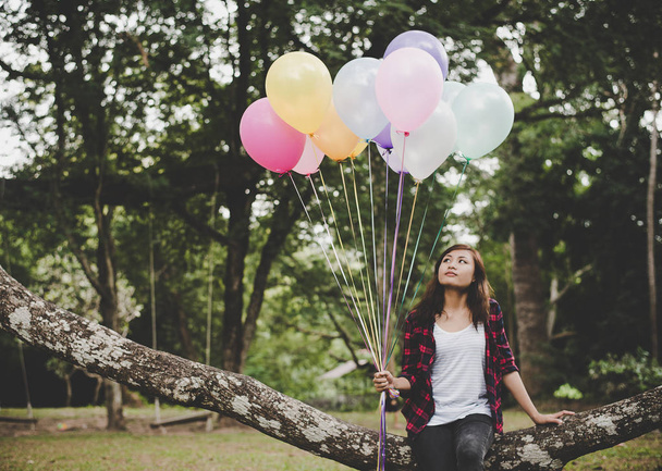Young hipster woman sitting on tree branch with colorful of ball - Photo, Image