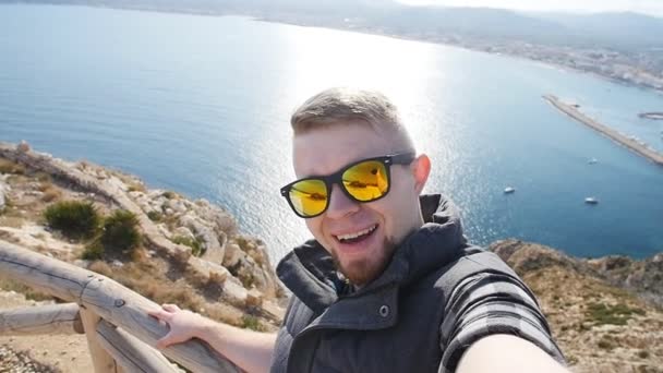 Fiatal ember vesz selfie utazás, trekking kirándulás nap. A háttérben a tenger és a sziklák - Felvétel, videó