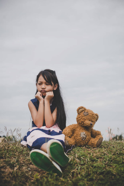 Jolie fille asiatique avec ours en peluche assis sur le champ de prairies. concept d'amitié
. - Photo, image