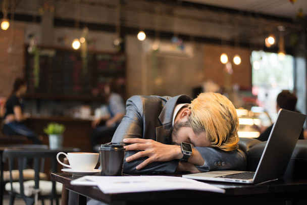 Cansado hombre de negocios taza tomar una siesta en la cafetería mientras trabaja con su computadora portátil
. - Foto, Imagen