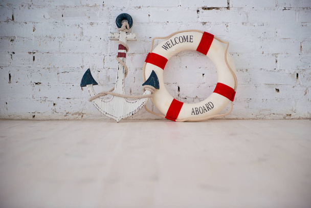 A composition on a sea theme with an anchor and life ring on a white brick wall. - Fotoğraf, Görsel