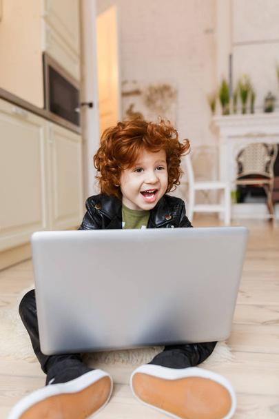 Little redhead boy uses a laptop - Photo, Image