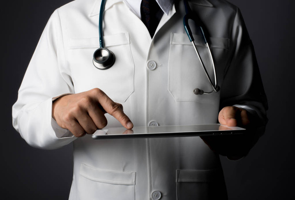 Молодой врач держит планшет, изолированный на сером
. - Фото, изображение