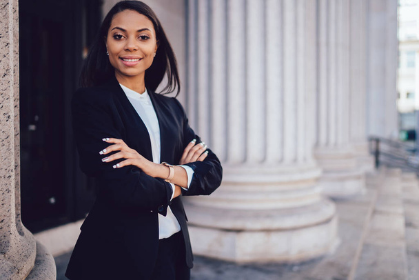 Half length portrait of successful happy businesswoman with dark skin crossed arms smiling at camera.Prosperous African American financial manager dressed in formal wear standing near copy space - Фото, зображення