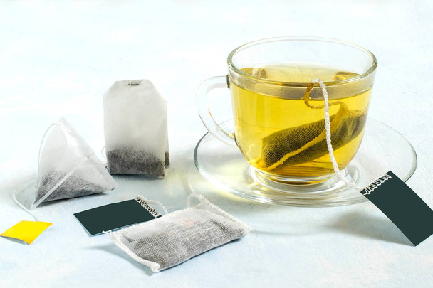 Több filteres tea és a csésze tea a fény kék háttér  - Fotó, kép