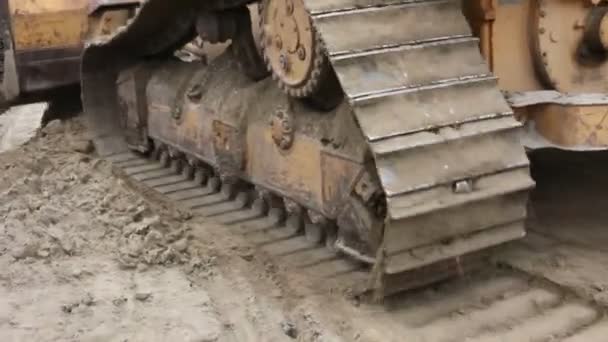 Crawler's tracks, bulldozer machine is leveling construction siteClose up view on bulldozer's undercarriage during pushing ground at construction site. - Footage, Video
