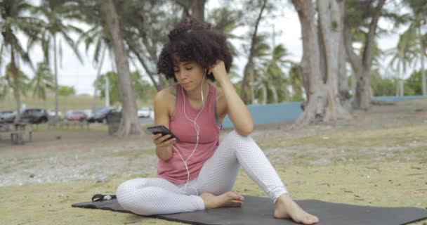 Охолоджуюча жінка з телефоном на килимку в парку
 - Кадри, відео