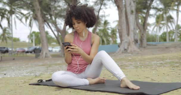 Ψύξη μαύρο κορίτσι χρησιμοποιώντας τηλέφωνο σε χαλί - Πλάνα, βίντεο