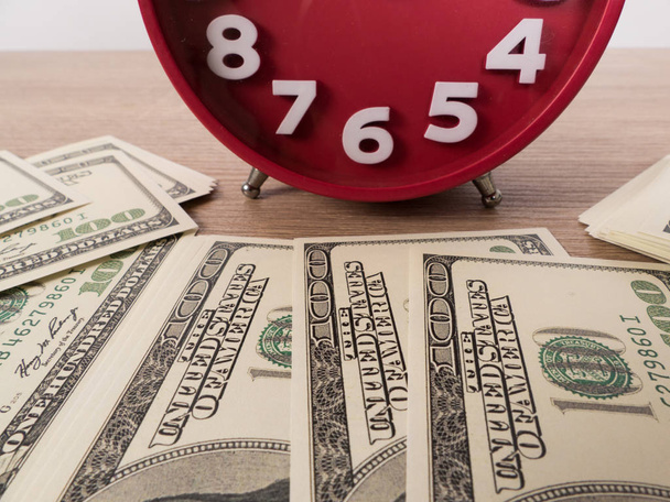 Доллар банкноты на столе и красный будильник
 - Фото, изображение