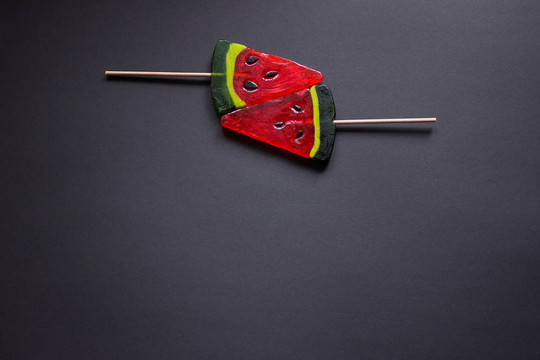 Two juicy lollipops in the shape of a watermelon on black backgr - Photo, image