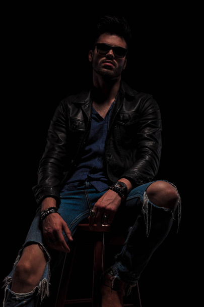 seated fashion man with sunglasses posing seductively - Zdjęcie, obraz