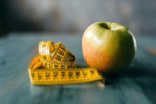 Apple i taśma pomiarowa na drewnianym stole zbliżenie, zasada diety utrata wagi - Zdjęcie, obraz