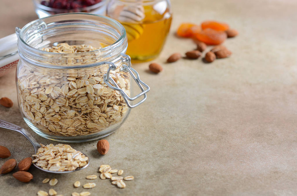 Ingredients for homemade oatmeal granola. Oat flakes, honey, almond nuts, dried cranberries and apricots. Healthy breakfast concept. - Foto, Bild