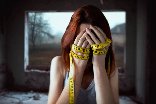 woman covering face with hands tied with measuring tape, weight loss - Foto, Imagem