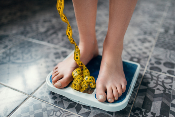 ženské nohy na váhy detailním krejčovským metrem, hubnutí, tvrdé diety - Fotografie, Obrázek