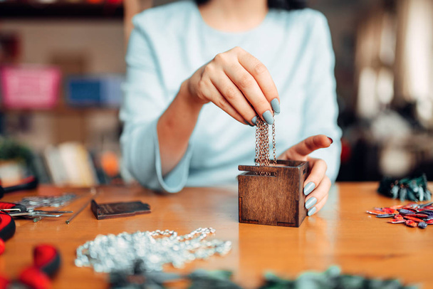 donna tirando fuori la catena di metallo dalla scatola di legno, maestro sul lavoro, gioielli fatti a mano
 - Foto, immagini