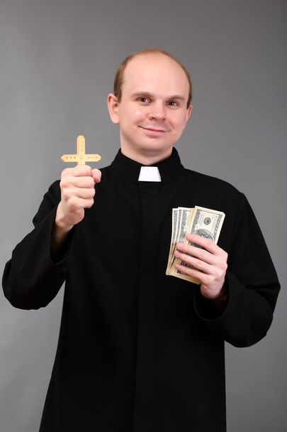 Young pastor with cross and money on gray background - Foto, Imagem