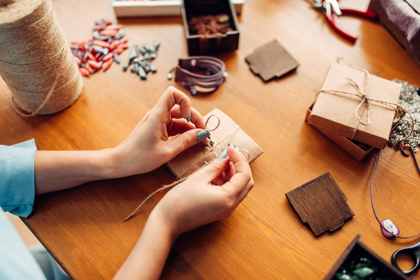 Frau fertigt Schleife auf einer Geschenkschachtel, Handarbeitsaccessoires - Foto, Bild
