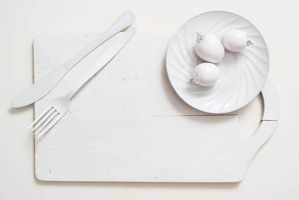 White fork knife plate on an old wooden plank tray. Art idea white tomatoes, all in one color - Фото, изображение