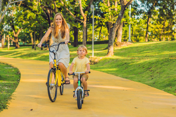 Mother and son riding bikes outdoors and smiling - Photo, Image