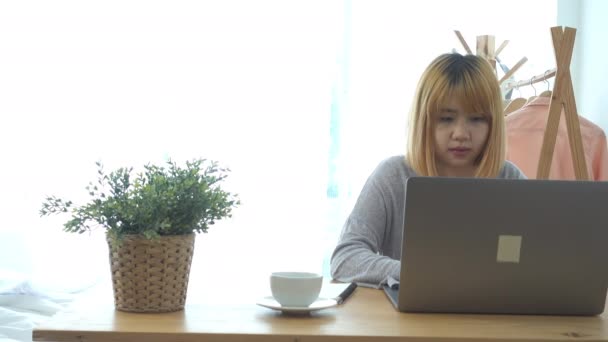 Όμορφη νεαρή χαμογελώντας ασιατική γυναίκα εργάζεται στον φορητό υπολογιστή ενώ στο σπίτι στο χώρο γραφείων εργασίας. Επιχειρηματίας που εργάζονται από το σπίτι μέσω φορητού υπολογιστή, γράφοντας στο πληκτρολόγιο. Απολαμβάνοντας χρόνο στο σπίτι. - Πλάνα, βίντεο
