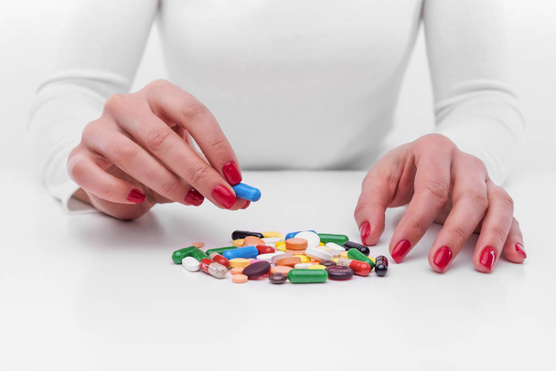 Woman chooses medicine from a handful of different color tablets. - Fotó, kép