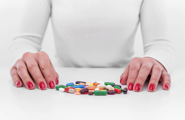 Woman chooses medicine from a handful of different color tablets. - Foto, Bild