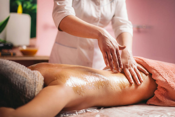 a masseur doing honey massage of back for client - Valokuva, kuva
