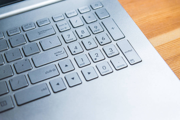 Крупный план детализации металлической клавиатуры ноутбука на деревянном столе для создания концепции бизнес-идеи
 - Фото, изображение